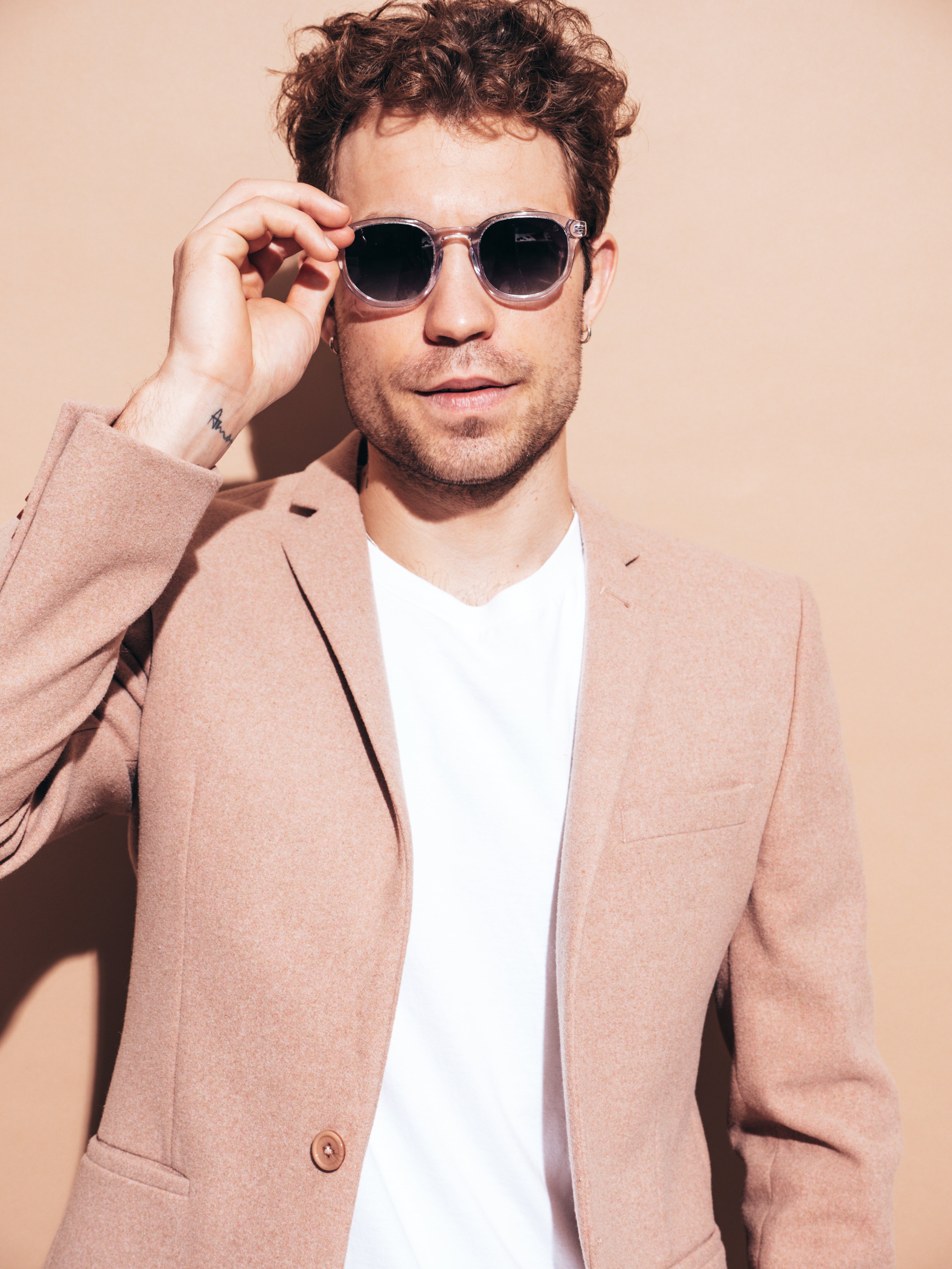 portrait-handsome-confident-stylish-hipster-lambersexual-model-sexy-modern-man-dressed-elegant-beige-suit-fashion-male-with-curly-hairstyle-posing-studio-isolated-sunglasses.jpg